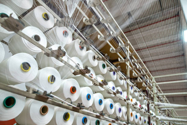 Textile yarn manufacturing, synthetic yarn, polyester and polypropylene production stages, yarn wound as bobbins. warp thread